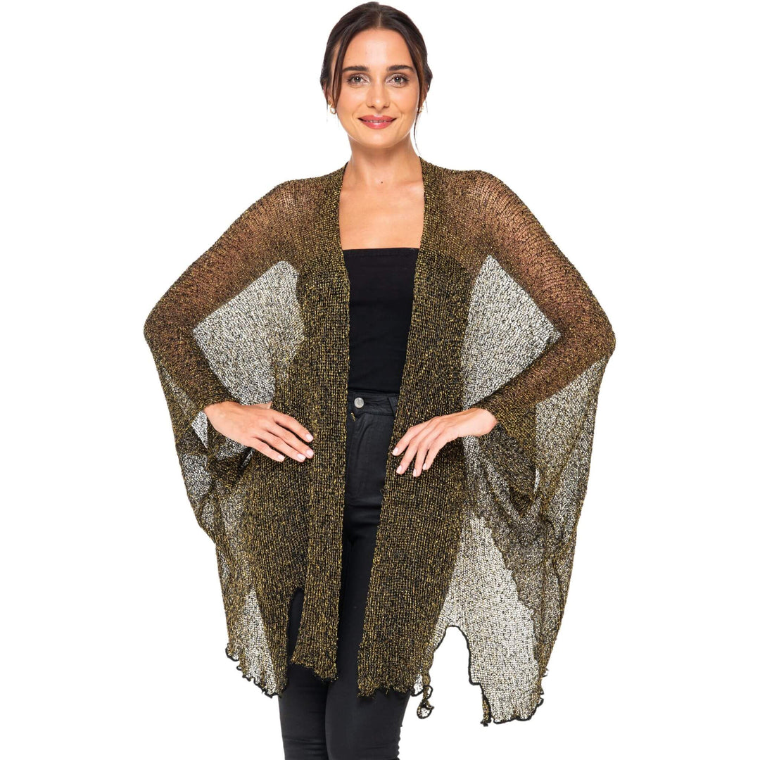 SHU-SHI black and gold metallic cardigan poncho with sheer sparkly panels worn open over a black top, displayed on a model against a white studio background.