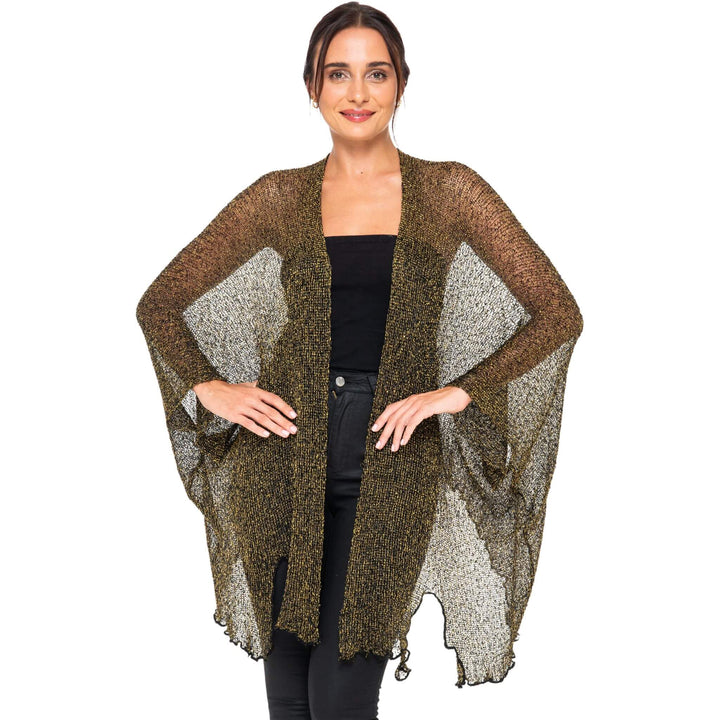SHU-SHI black and gold metallic cardigan poncho with sheer sparkly panels worn open over a black top, displayed on a model against a white studio background.