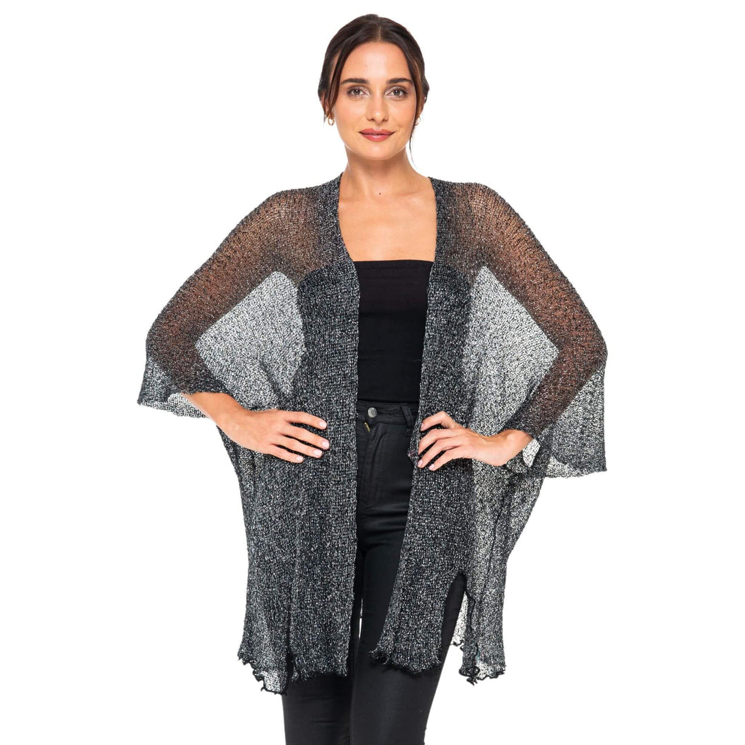 SHU-SHI black and gold metallic cardigan poncho with sheer sparkly fabric and color-block design, worn open over a black top and pants against a white studio background.