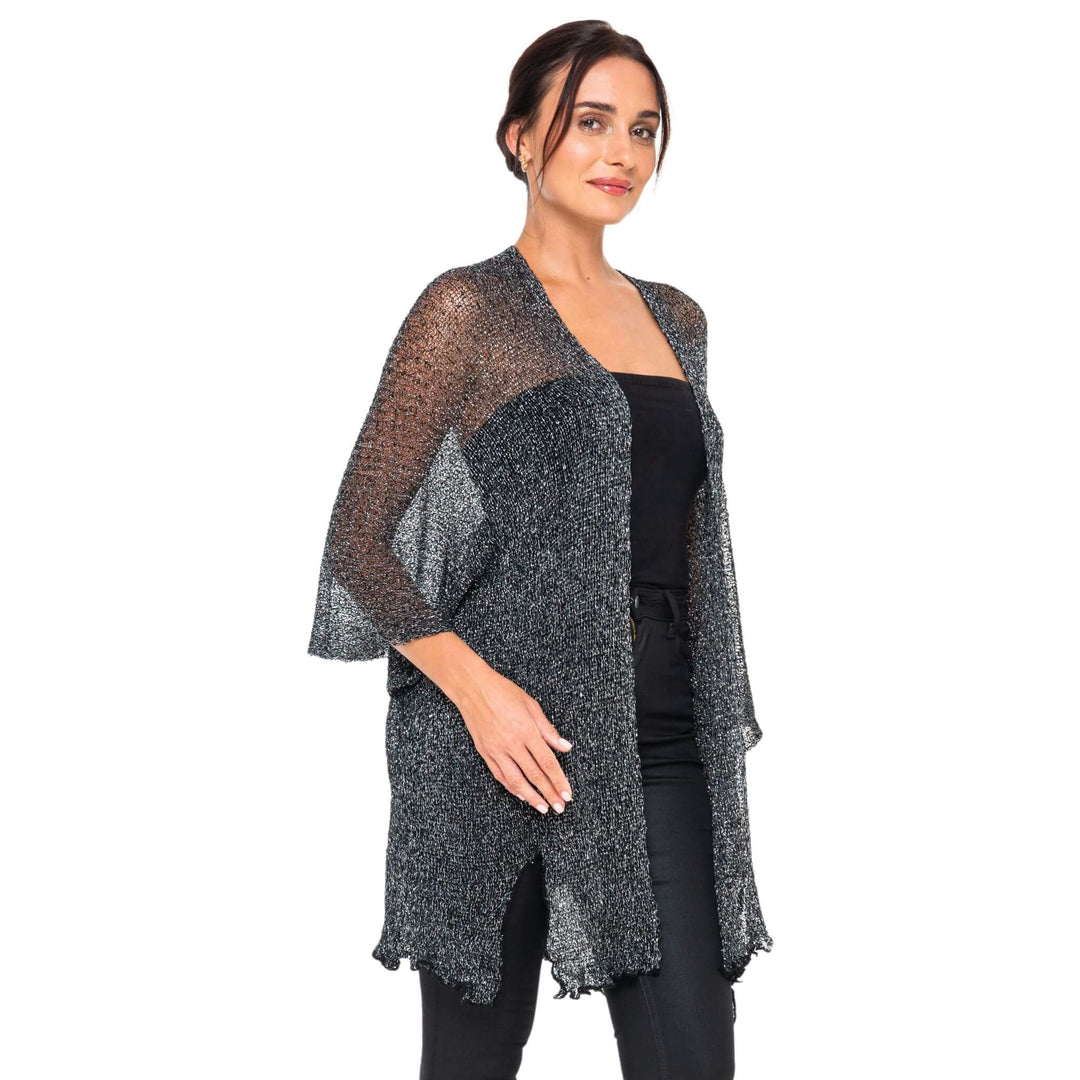 SHU-SHI black-gold metallic cardigan with lightweight sparkly fabric worn open over a black dress, styled on a model against a white studio background.