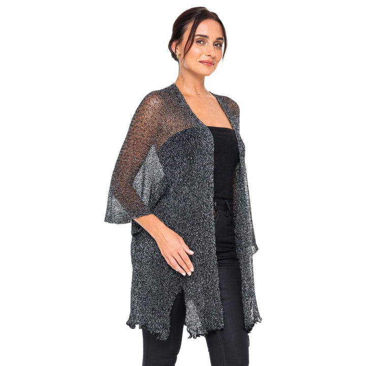 SHU-SHI black-gold metallic cardigan with lightweight sparkly fabric worn open over a black dress, styled on a model against a white studio background.