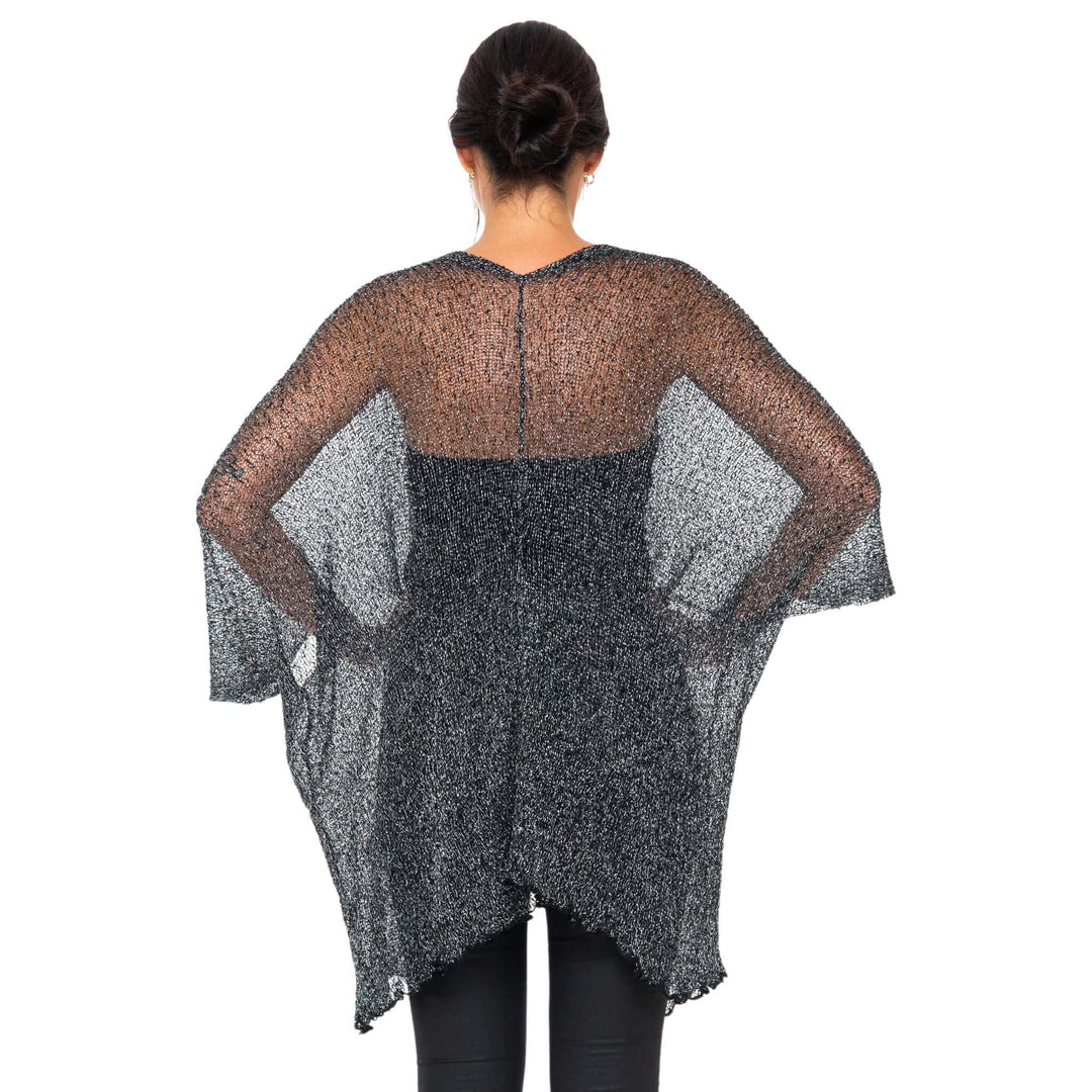 SHU-SHI black and gold metallic cardigan with sheer lightweight fabric and draped sleeves shown from back on model wearing black leggings against white studio background.