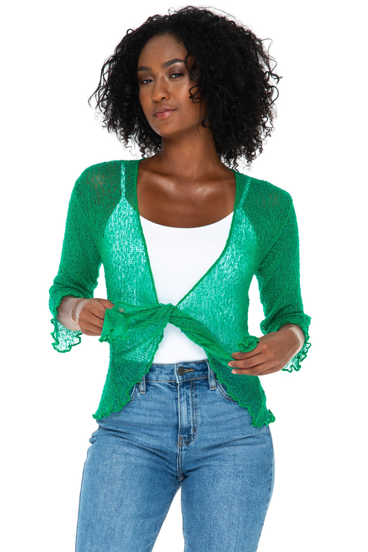 A woman modeling a SHU-SHI Emerald green sheer knit cardigan with front tie, worn over a white top and blue jeans, on a solid white background.
