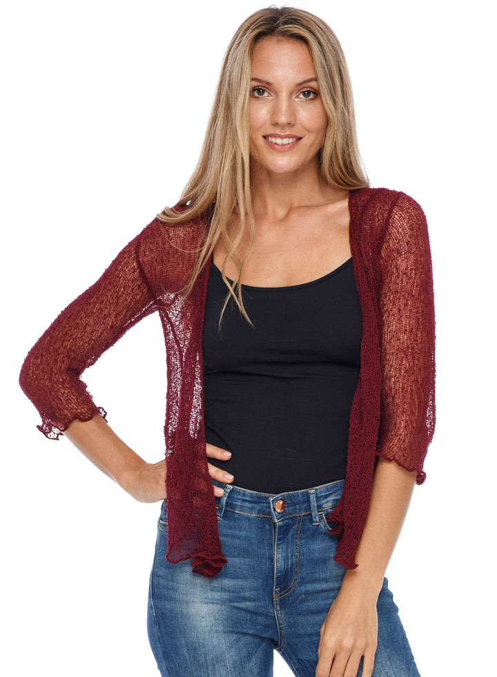 A woman modeling a sheer, open-front SHU-SHI cardigan in maroon over a black tank top and blue jeans, shot against a solid white background.