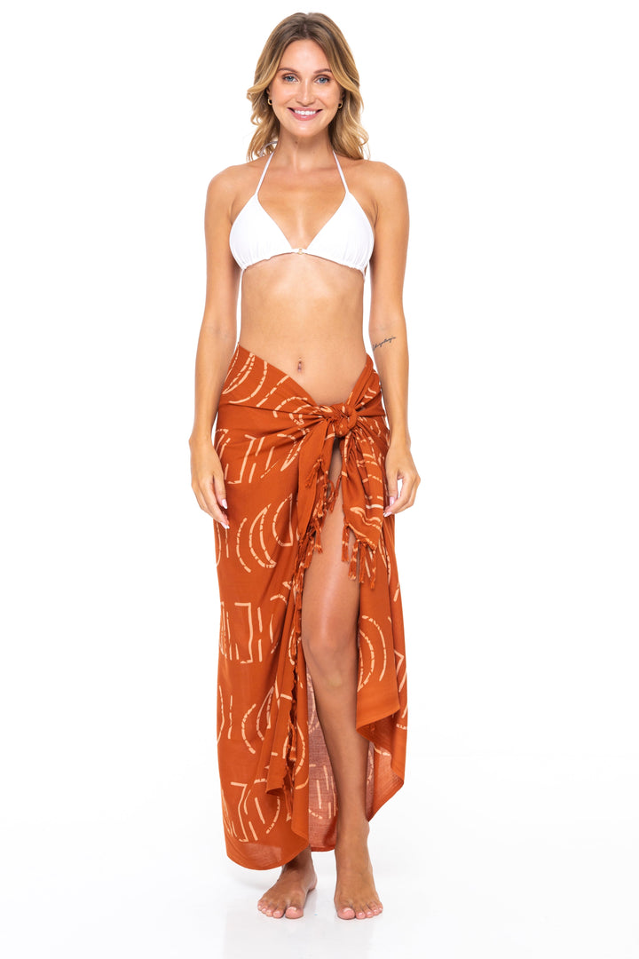 Woman wearing a white bikini top and SHU-SHI moon print sarong in Ginger on a white background - front view